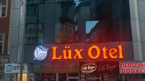 Hotel Lux Otel, con fachada de vidrio moderna que refleja edificios cercanos.