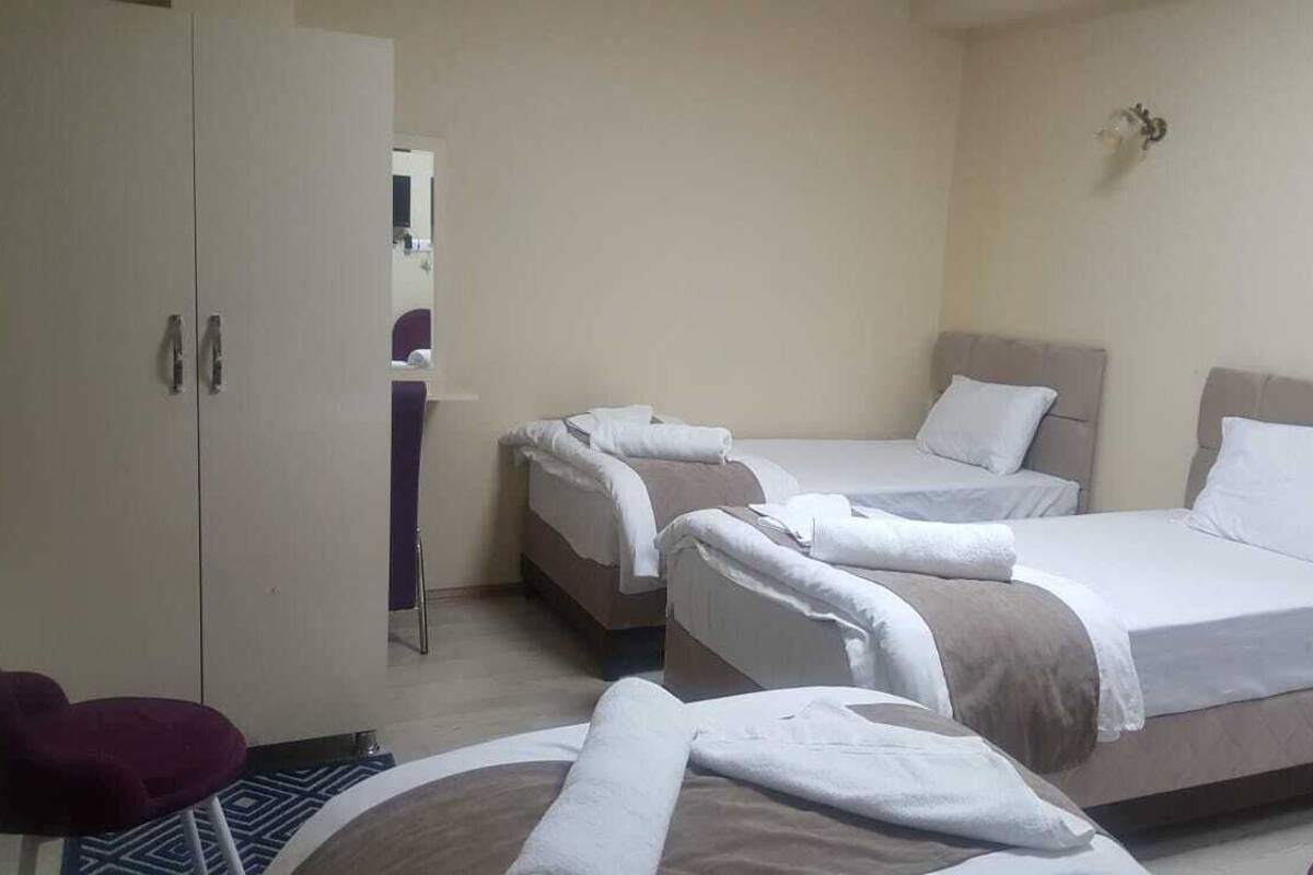A hotel room with two beds, a wardrobe, and a small seating area.