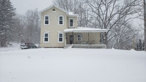 A two-story house with a porch and a snow-covered roof.