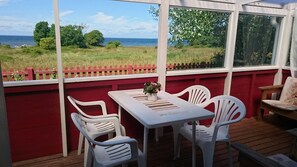 A covered patio with a table and chairs, a view of the sea, and a red fence. - A pearl by the sea ! (Köpingsvik)