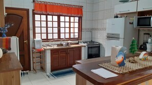 Una cocina con ventana, pileta, estufa, refrigerador y microondas.