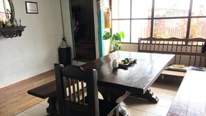A dining area with a long wooden table, chairs, and a potted plant. - Hostal Familiar Jerico (Salento)