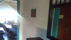 A room with a wooden bench, a small table with a newspaper, a door with a sign, and a window allowing natural light. - Hostal Familiar Jerico (Salento)