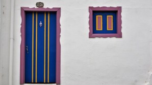 A building with a blue door with yellow stripes and a small window with two doors. - Hostal Familiar Jerico (Salento)