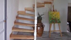 Una escalera de madera con barandilla blanca, una planta en maceta y un caballete con un cuadro.