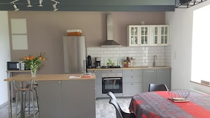 Una cocina moderna con una isla central, armarios grises y una zona de comedor con mantel rojo.