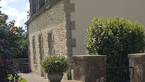 Un edificio de piedra con un estilo arquitectónico tradicional, que presenta un muro de piedra y una reja de metal.