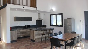 A modern kitchen with a wooden island, black bar stools, and a dining table. - Villa located in the heart of Provence with private pool on 3 hectares. (Roquevaire)
