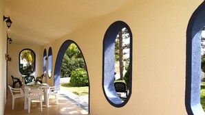 A covered outdoor area with a table and chairs, surrounded by arches with windows. - Villa Concita Sicily (viale malta)