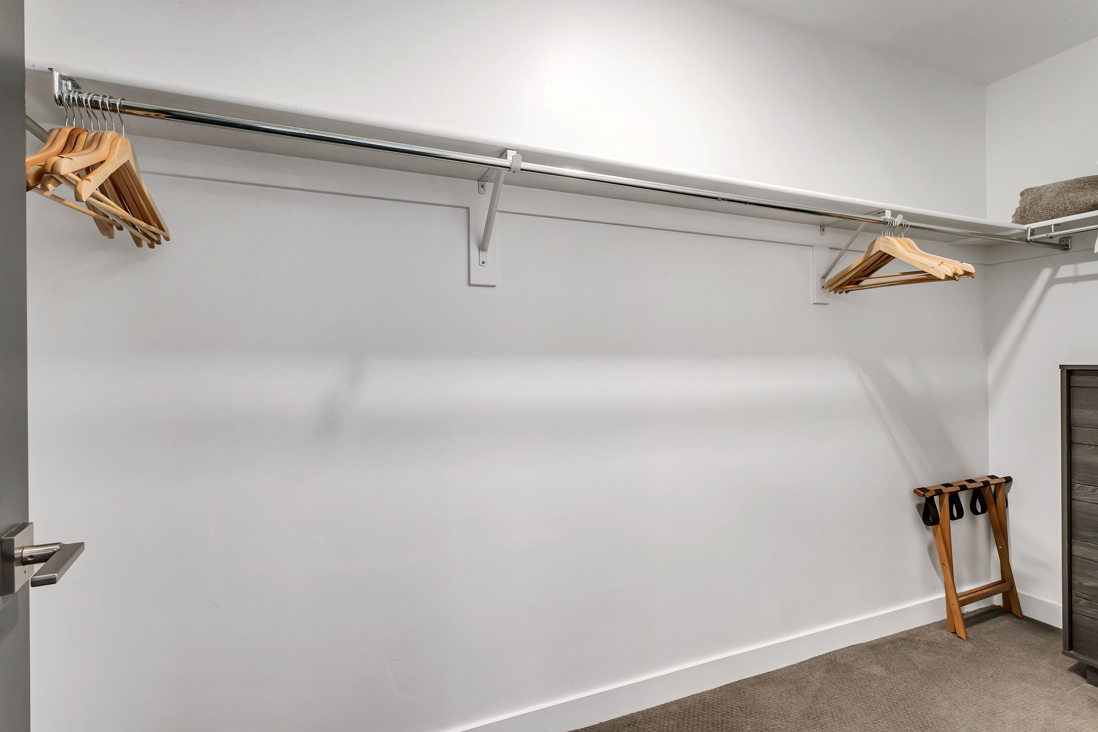 A minimalist closet with a metal rod and wooden hangers.