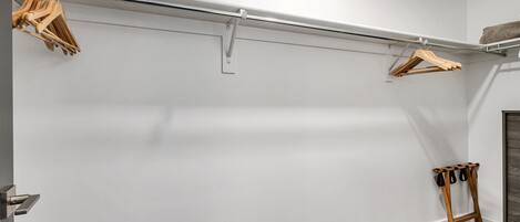 A minimalist closet with a metal rod and wooden hangers.