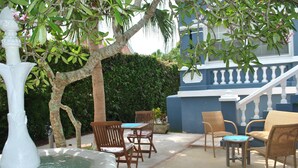 A patio with wicker furniture, a fountain, and a staircase leading to a blue building. - Your very own private space in Bermuda with Twizy charger (Warwick Parish)