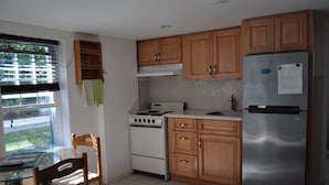 A kitchen with wooden cabinets, a stainless steel refrigerator, a stove, and a window with blinds. - Your very own private space in Bermuda with Twizy charger (Warwick Parish)