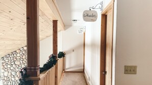 A narrow hallway with wooden railings, a stone wall, and a carpeted floor. - Beautiful OHV Friendly Lodge, Sun Room, Close Walk to River, Deck, Fire Pit (South Fork)