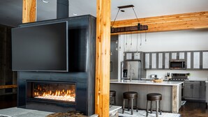 Eine moderne Küche mit Kamin aus Stein, Holzbalken und einer Bar mit Hockern.