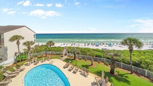 A pool area with lounge chairs, a view of the beach, and a clear sky. - Grand Playa 301, Scenic 30A, Gulf Front Condo, Pool with Private Beach Access (Seagrove Beach)