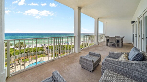 A balcony with a view of the ocean and beach, wicker furniture, and a pool. - Grand Playa 301, Scenic 30A, Gulf Front Condo, Pool with Private Beach Access (Seagrove Beach)