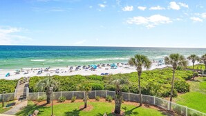A beach with umbrellas, palm trees, and a wooden deck. - Grand Playa 301, Scenic 30A, Gulf Front Condo, Pool with Private Beach Access (Seagrove Beach)