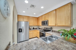 A modern kitchen with wooden cabinets, stainless steel appliances, granite countertops, and a built-in sink.