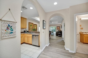 A modern kitchen with wooden cabinets, a dishwasher, and a dining area with a table and chairs.