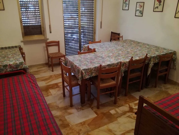 Un comedor con una mesa cubierta por un mantel floral, rodeado de sillas de madera.