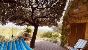 Una hamaca, terraza de madera y sillas en una terraza con vistas.