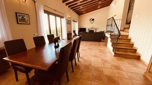 Un amplio comedor con una mesa y sillas de madera, una chimenea y una escalera que sube a un nivel superior.