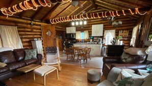 L’intérieur d’un chalet confortable, avec des murs en bois, une salle à manger en bois, un canapé et un banc.