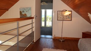 Une pièce avec un plafond en pente, un escalier doté de rampes en métal, un lampadaire et un tableau accroché au mur.