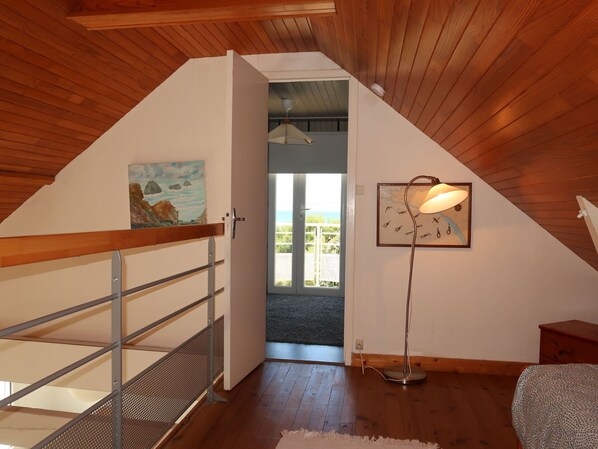 A room with a sloped ceiling, a staircase with metal railings, a floor lamp, and a painting on the wall.