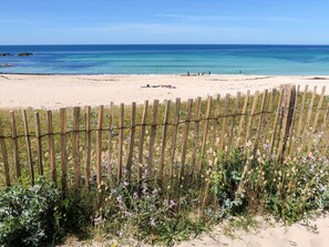 A beach with a wooden fence and a sandy shore.