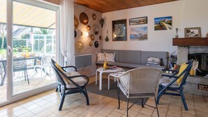A spacious living room with a wooden ceiling, a large sliding glass door leading to a patio, a fireplace, and various wall decorations. - Beautiful private villa for 6 guests with WIFI, TV, terrace and pets allowed (Saint-Égarec)