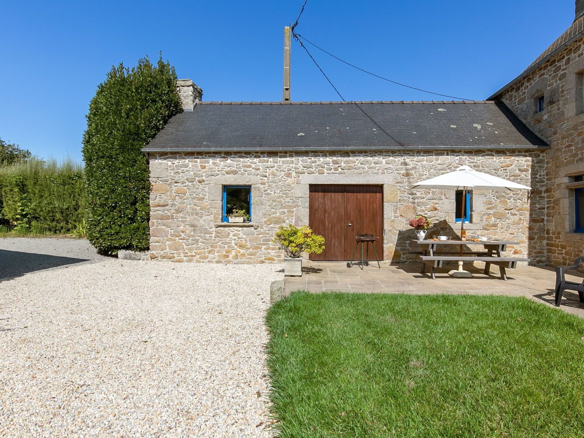 A stone building with a gravel driveway and a grassy lawn.
