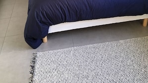 A neatly made bed with a dark blue bedspread and two pillows, flanked by white nightstands with lamps.