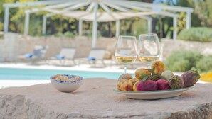 A dining table with a plate of food and two wine glasses, a bowl, and a white umbrella structure in the background.
