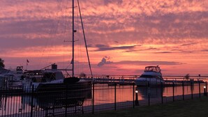 A marina with boats docked, a fence, and a sunset sky.