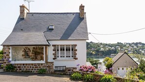 Een huis met twee verdiepingen, een gevel van natuursteen, een groot erker en een klein balkon.