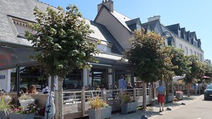 Un restaurante con terraza al aire libre, rodeado de árboles y edificios.