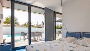 Un dormitorio con cama, escritorio y vistas a una piscina y zona de estar exterior.