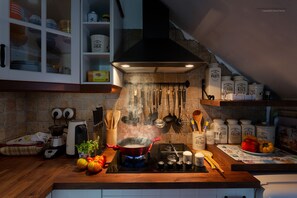 A kitchen with a gas stove, a range hood, and various cooking utensils.