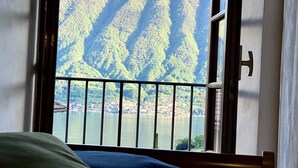Ein Zimmer mit einem Bett, einem Fenster und Blick auf einen Berg und einen See.