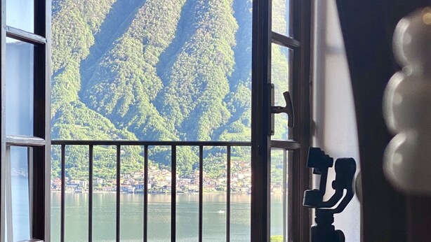 Ein Zimmer mit einem Bett, einem Fenster mit Seeblick und Bergblick sowie einem Balkon mit Geländer.