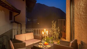 Eine Terrasse im Freien mit Korbmöbeln, einer Feuerstelle und einem Esstisch.
