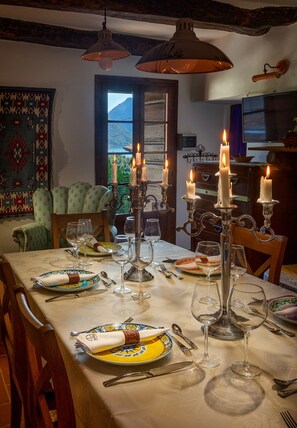 A dining room with a table set for a meal, candles, and a view of the outdoors.