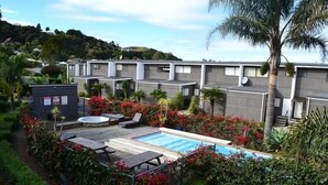 A residential area with modern houses, a swimming pool, and lush greenery.