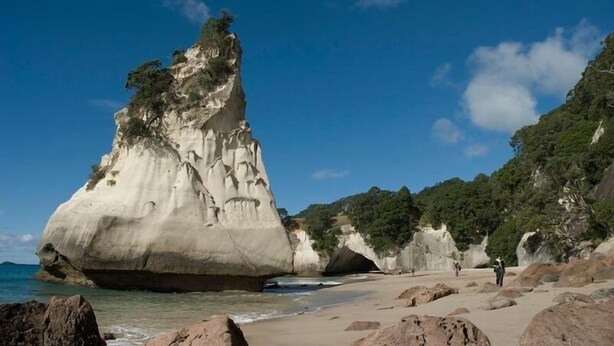 A coastal landscape with a prominent rock formation and a beach.