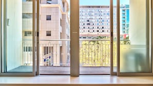 Uitzicht vanaf een balkon met een metalen hekwerk, een houten terras, en een gebouw met meerdere verdiepingen en balkons op de achtergrond.