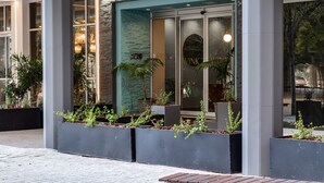 Een modern gebouw met een stenen gevel, grote ramen en binnenplanten.