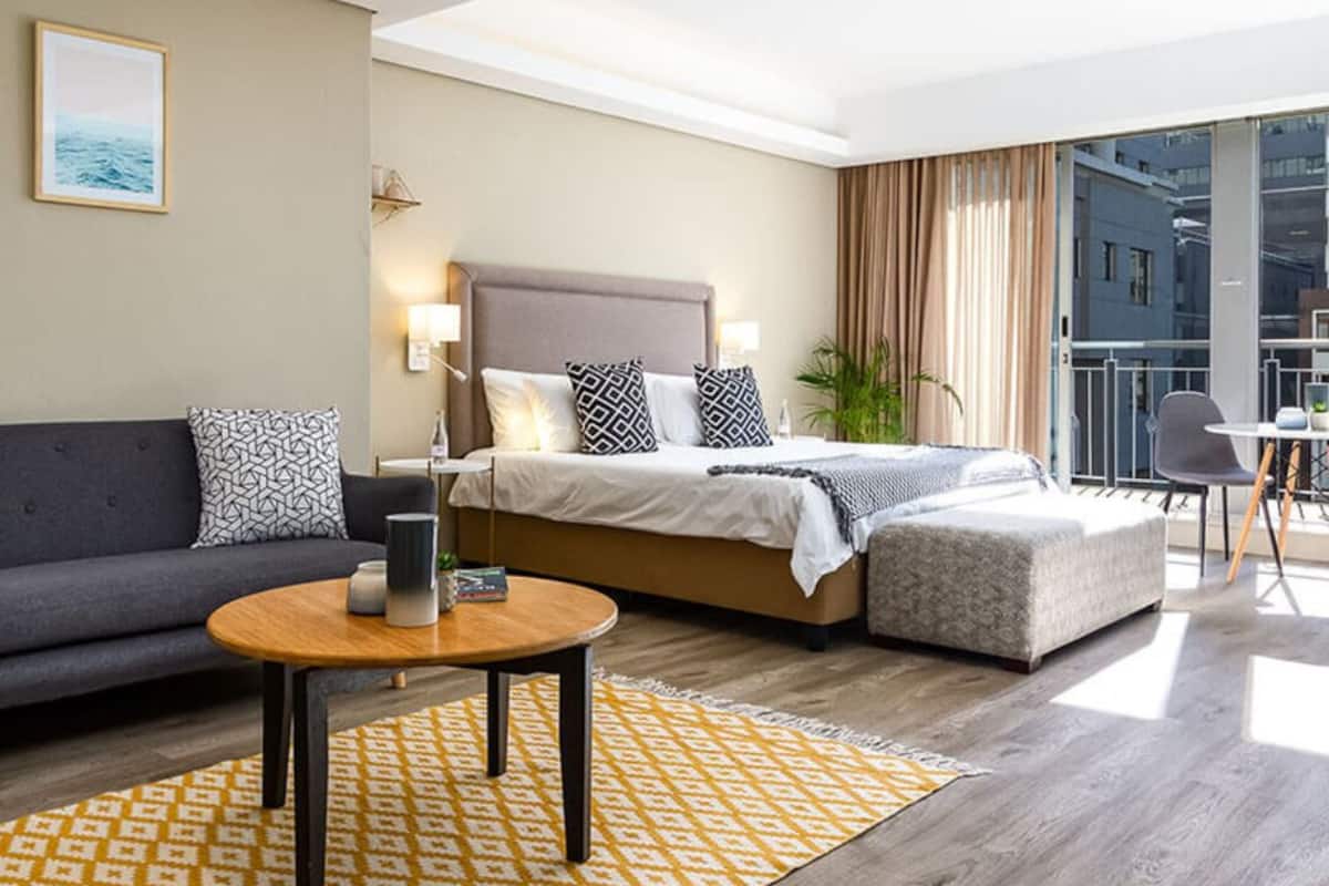Ein modernes Hotelzimmer mit Bett, Sofa und einem kleinen Tisch.