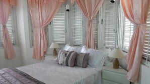 A bedroom with a bed, bedside tables, lamps, and curtains. - Chill on tha hill/ free wi fi <br>A/c, free wi fi, gated community  (ocho rios)